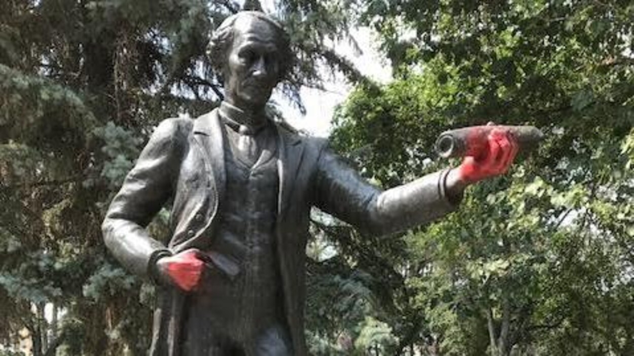 Statue de John A. Macdonald au centre-ville de Regina, dont les mains sont recouvertes de peinture rouge. Statue de John A. Macdonald au centre-ville de Regina, dont les mains sont recouvertes de peinture rouge.