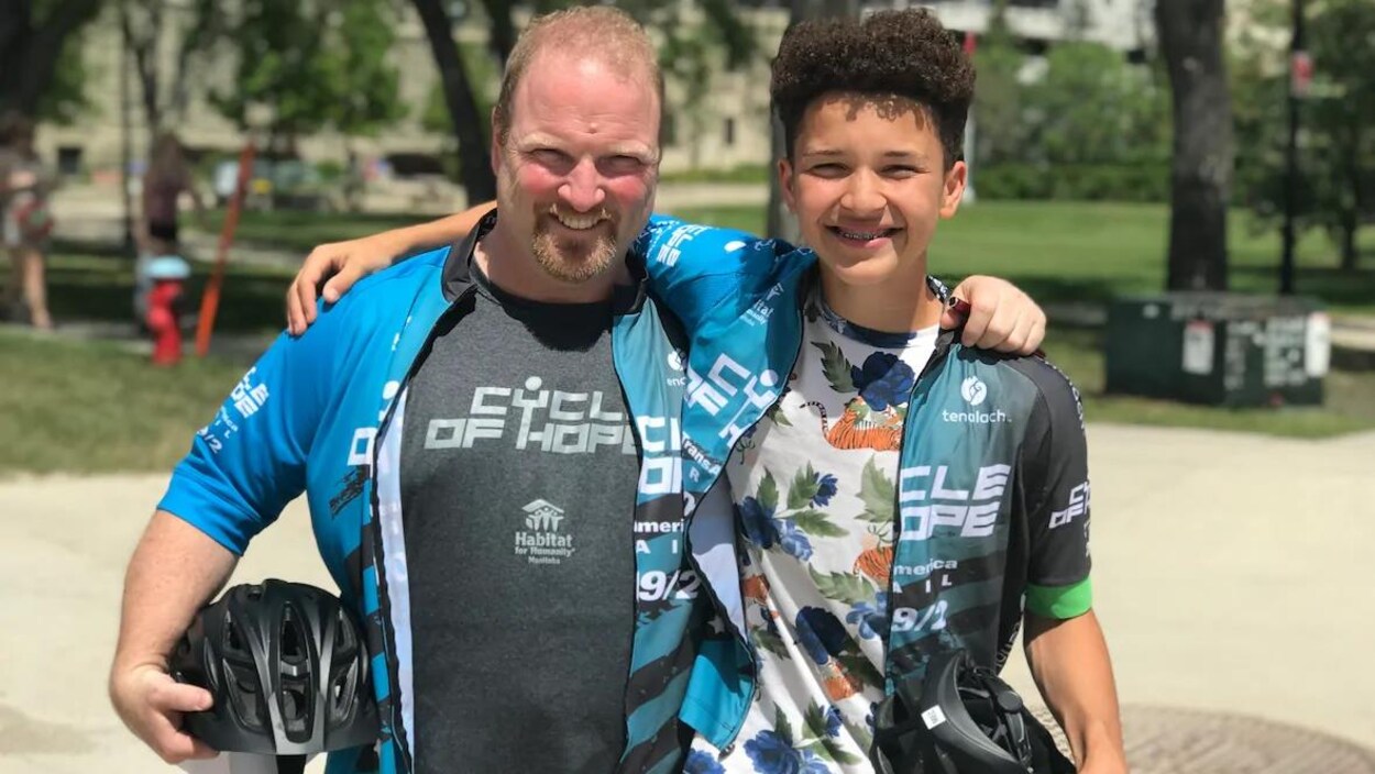 John Loewen et son fils Sam se tiennent par le cou, un casque de vélo à la main.