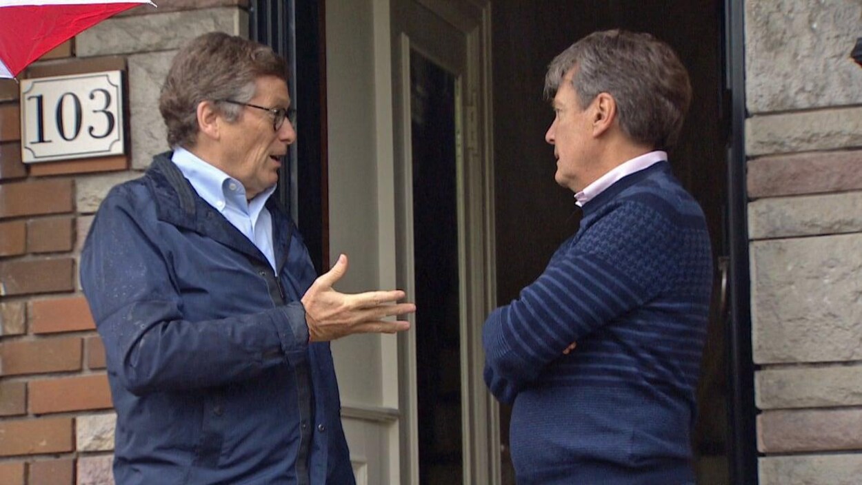 Le maire Tory avec un autre homme parle sur le perron d'une maison.