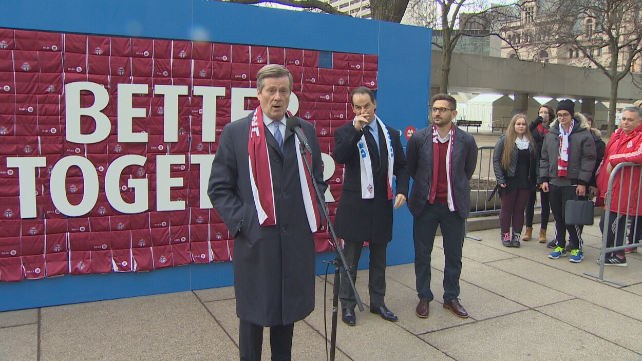 Le maire John Tory se tient à l'extérieur devant une affiche qui dit «Meilleur ensemble».