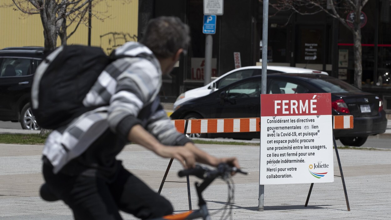 Une homme passe à vélo devant une place publique fermée.