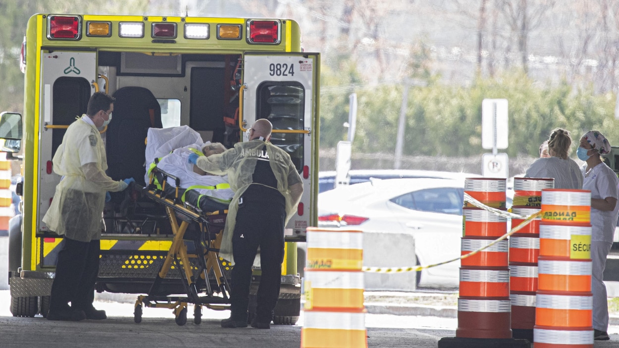 Des ambulanciers s'apprêtent à installer un patient dans une ambulance.