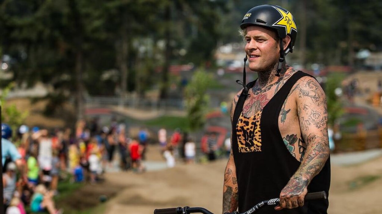 Un cycliste tatoué portant un casque dans un parc de vélo.
