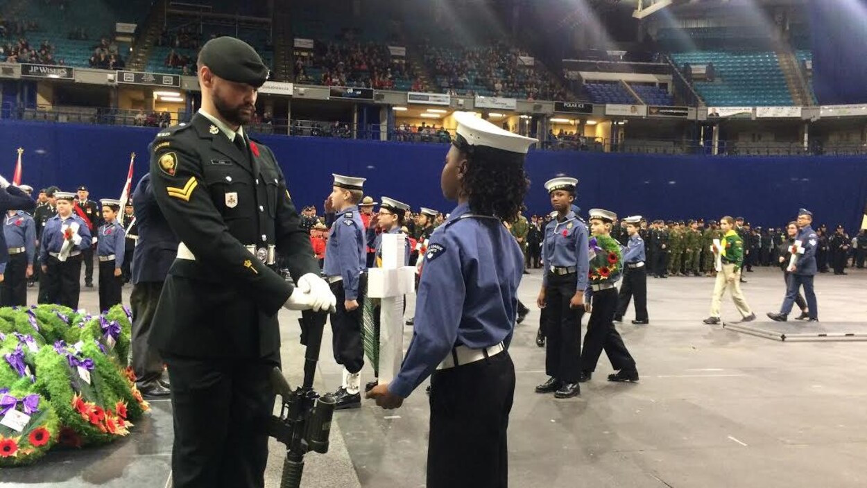Un soldat et des jeunes défilent au centre de l'aire de jeu d'un stade.