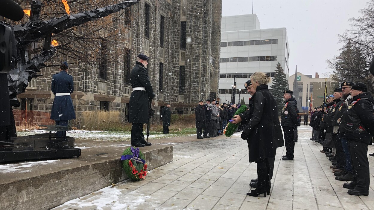 Des militaires déposent une couronne devant l'hôtel de ville.