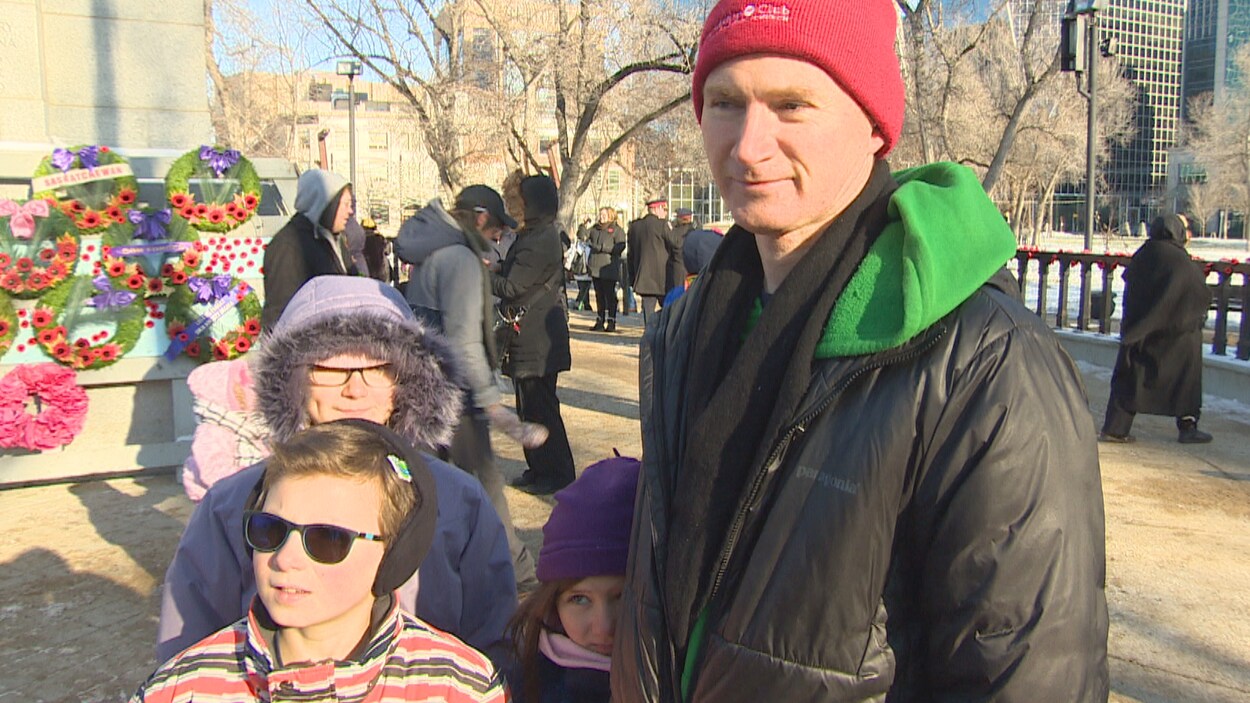 Un homme avec trois enfants devant le cénotaphe de la place Victoria, à Regina.