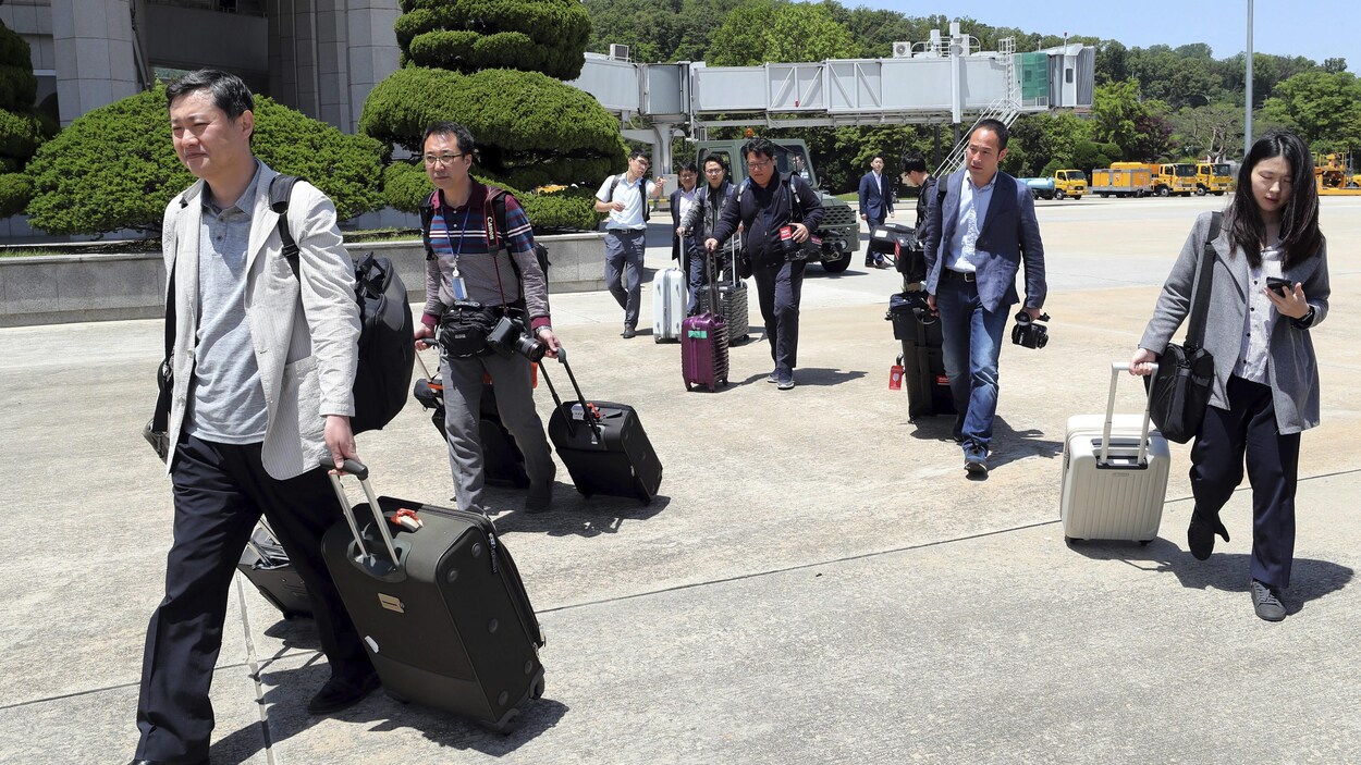Une dizaine de journalistes marchent avec leur valise sur le tarmac de l'aéroport de Seongnam. Une dizaine de journalistes marchent avec leur valise sur le tarmac de l'aéroport de Seongnam.