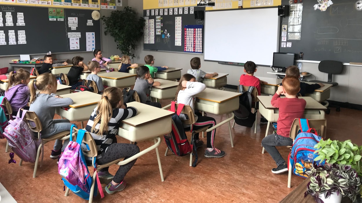 Des élèves regardent vers le tableau dans une classe du primaire.