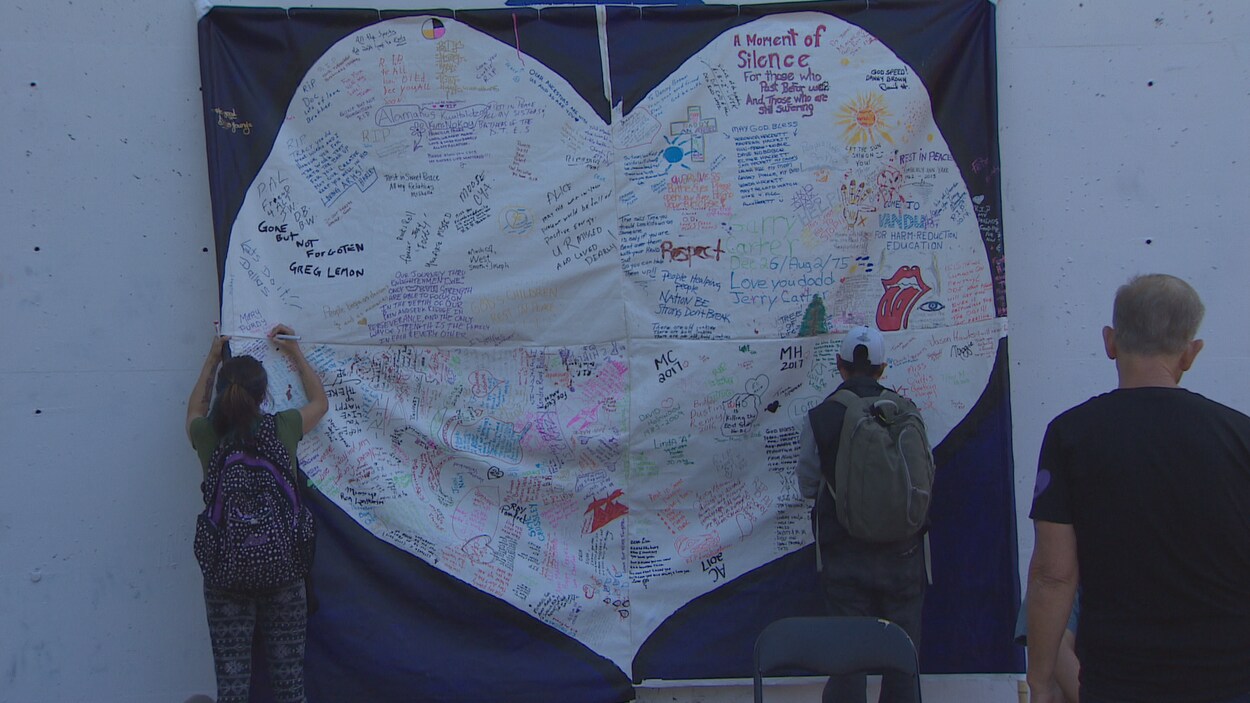 Des gens signent une murale en forme de coeur à Vancouver en souvenir de gens morts par surdose