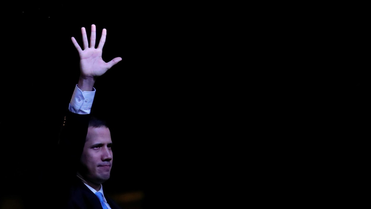 Juand Guaido lève la main lors d'un rassemblement en pleine nuit.