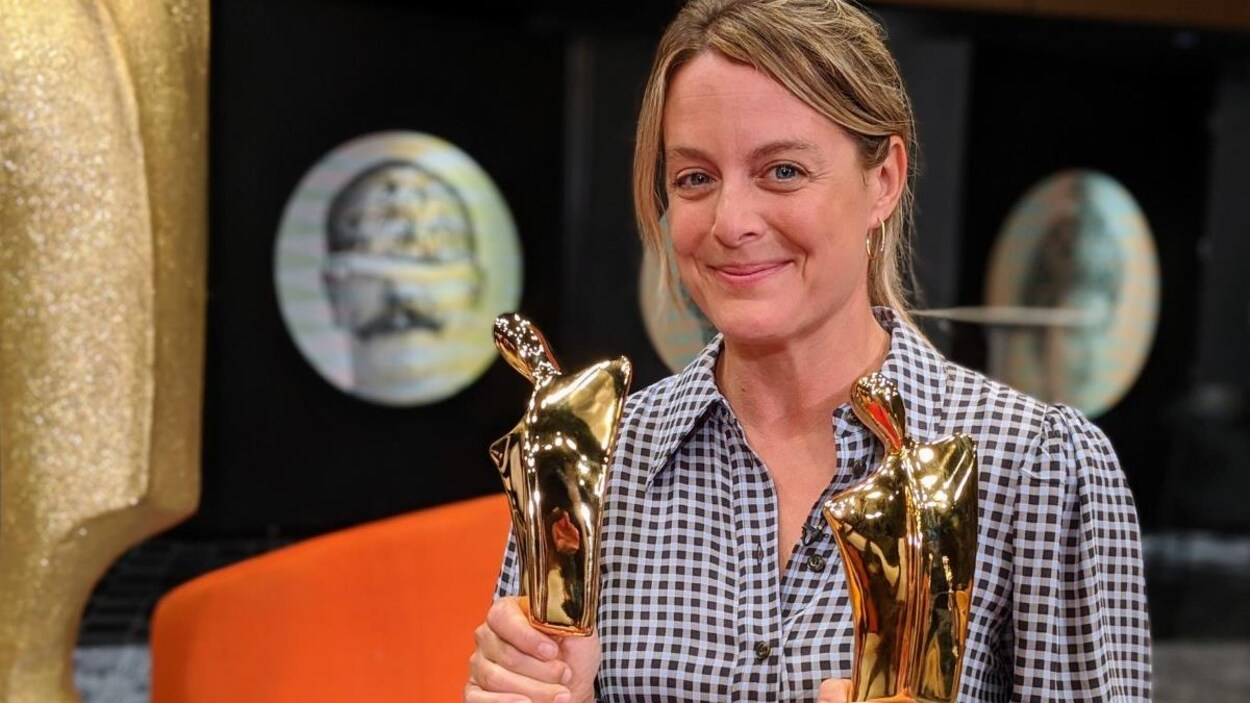 La comédienne tient deux statuettes dorées dans ses mains.