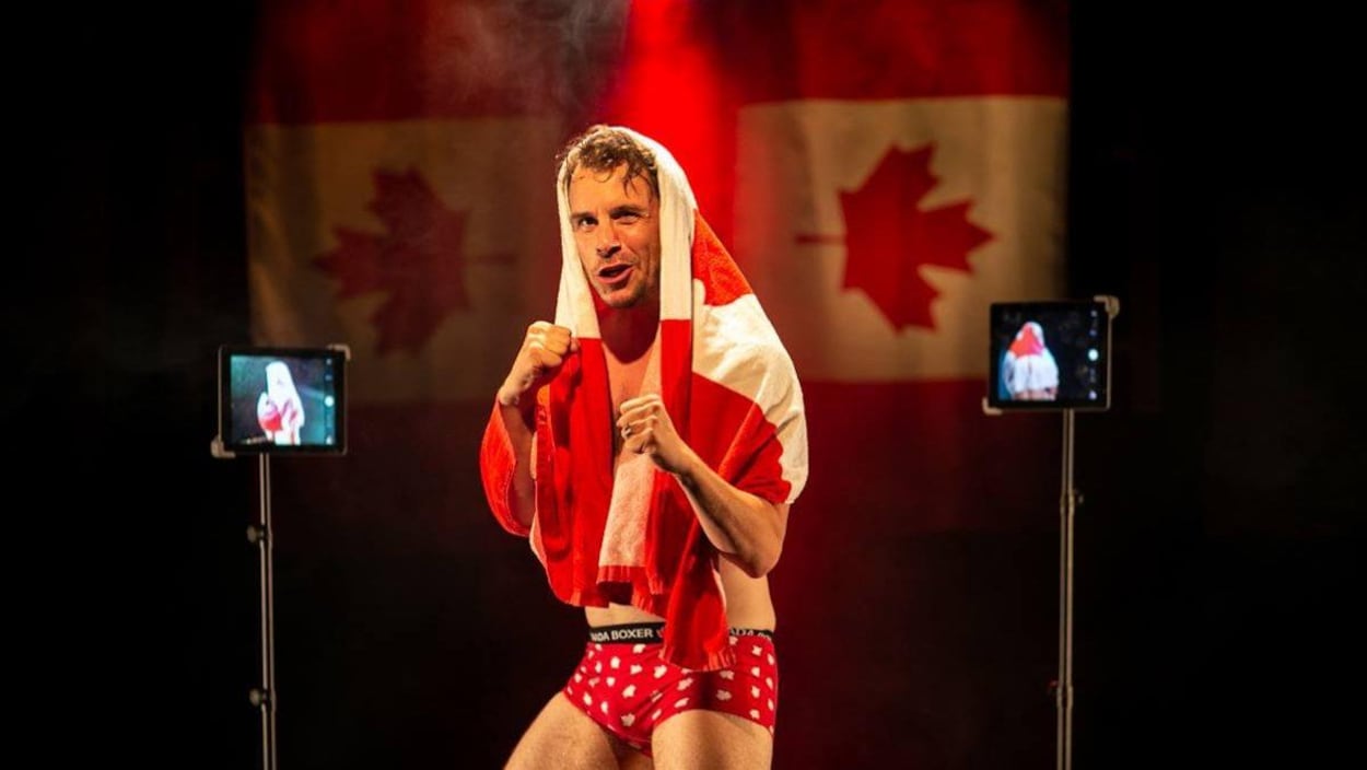 Un homme vêtu de caleçons se tient en position de boxe avec un drapeau canadien sur la tête.