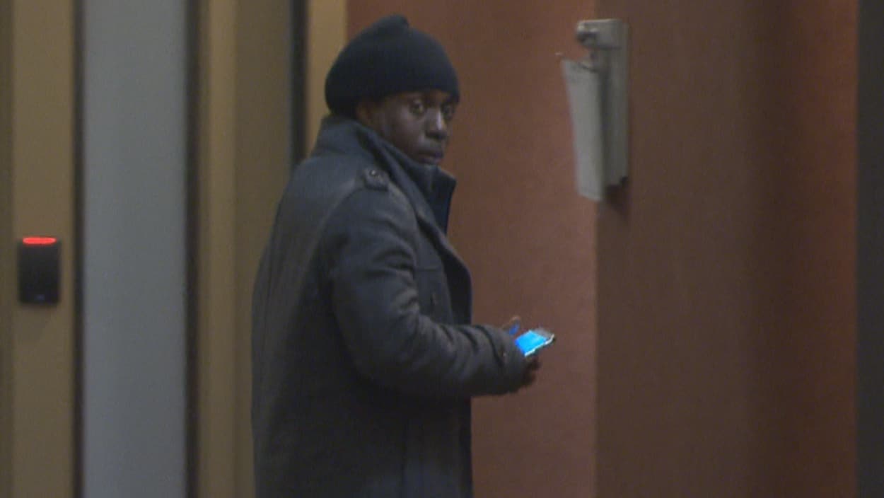 Un homme portant un manteau et une tuque dans un corridor.