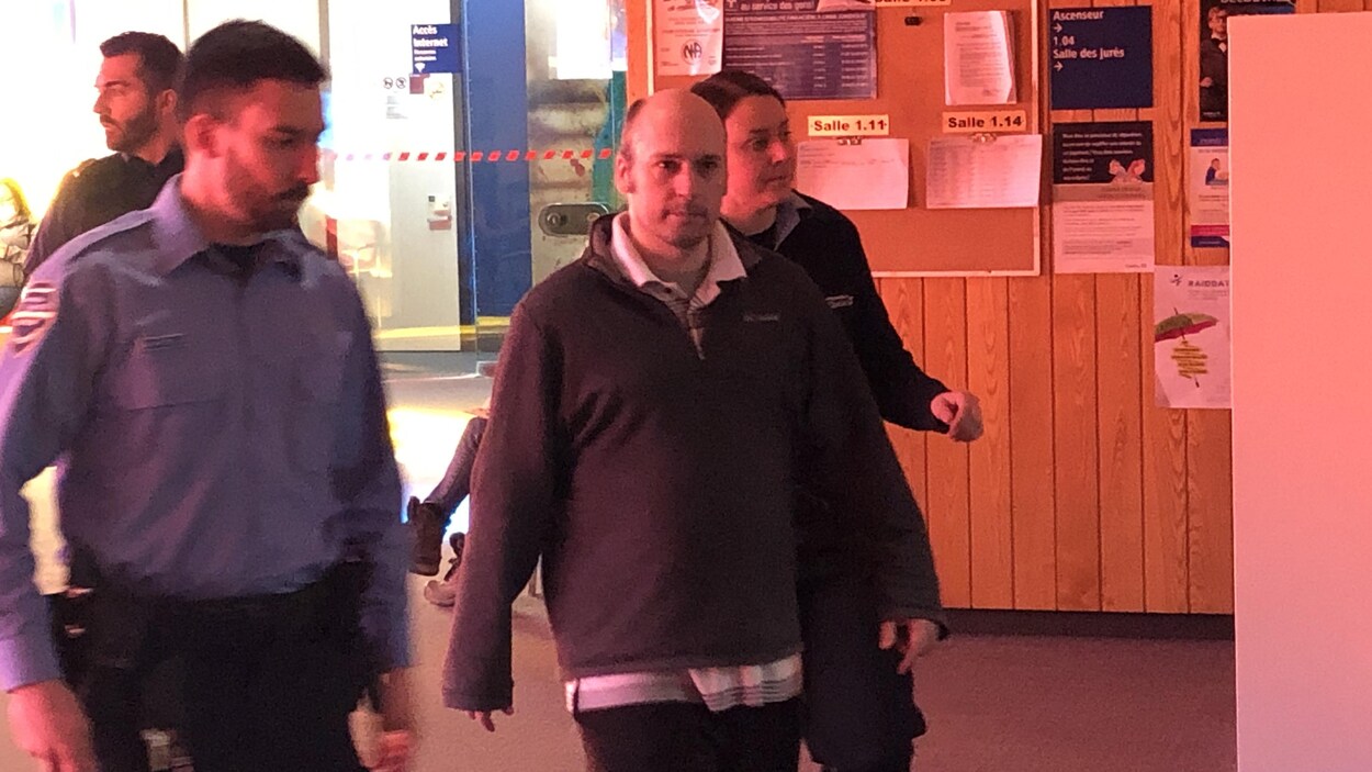 Un homme et des policiers dans le palais de justice d'Amos.