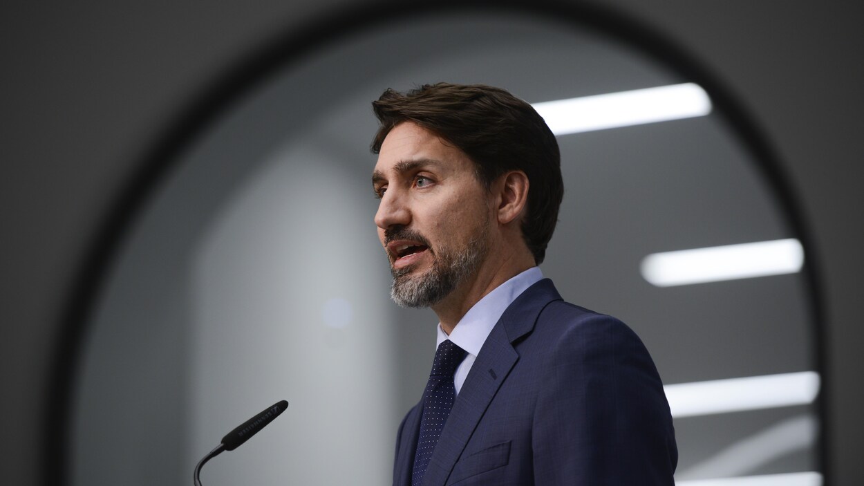 Plan moyen de Justin Trudeau devant un micro.