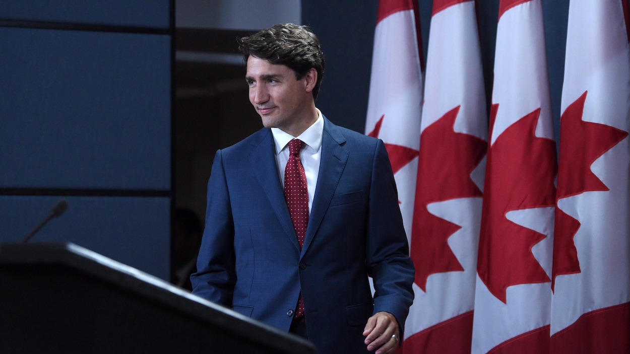 Le premier ministre Justin Trudeau s'avance en souriant devant une série de drapeaux canadiens, lors d'une conférence de presse à Ottawa, le 19 septembre 2017. Le premier ministre Justin Trudeau s'avance en souriant devant une série de drapeaux canadiens, lors d'une conférence de presse à Ottawa, le 19 septembre 2017.