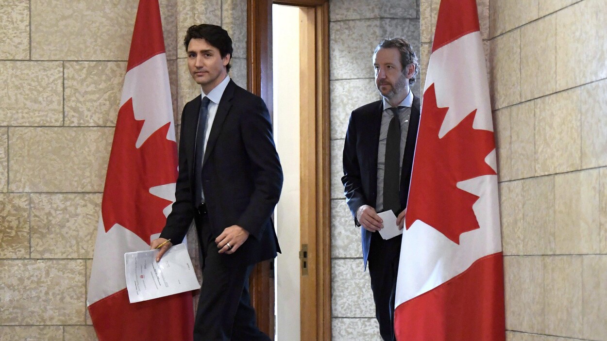 Justin Trudeau et Gerald Butts encadrés de deux drapeaux canadiens. Justin Trudeau et Gerald Butts encadrés de deux drapeaux canadiens.