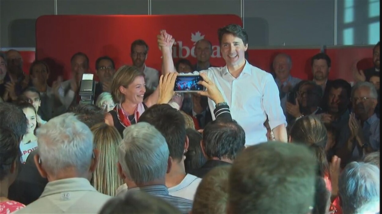 Entouré d'une foule de partisans, le premier ministre tient la main de sa collègue haut dans les airs.