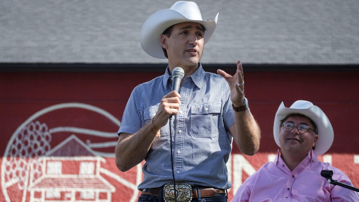 Deux hommes portant un chapeau de cowboy, l'un assis, l'autre debout.