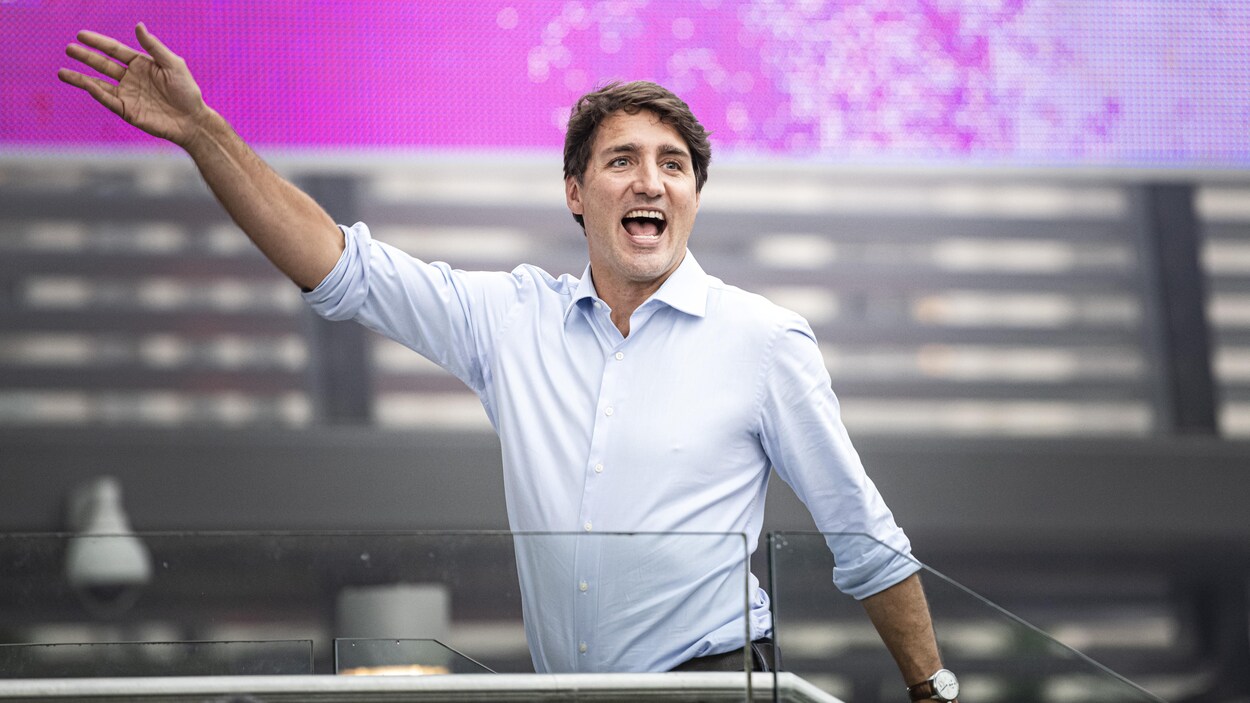 Justin Trudeau marc he sur une scène le bras levé et le sourire aux lèvres.