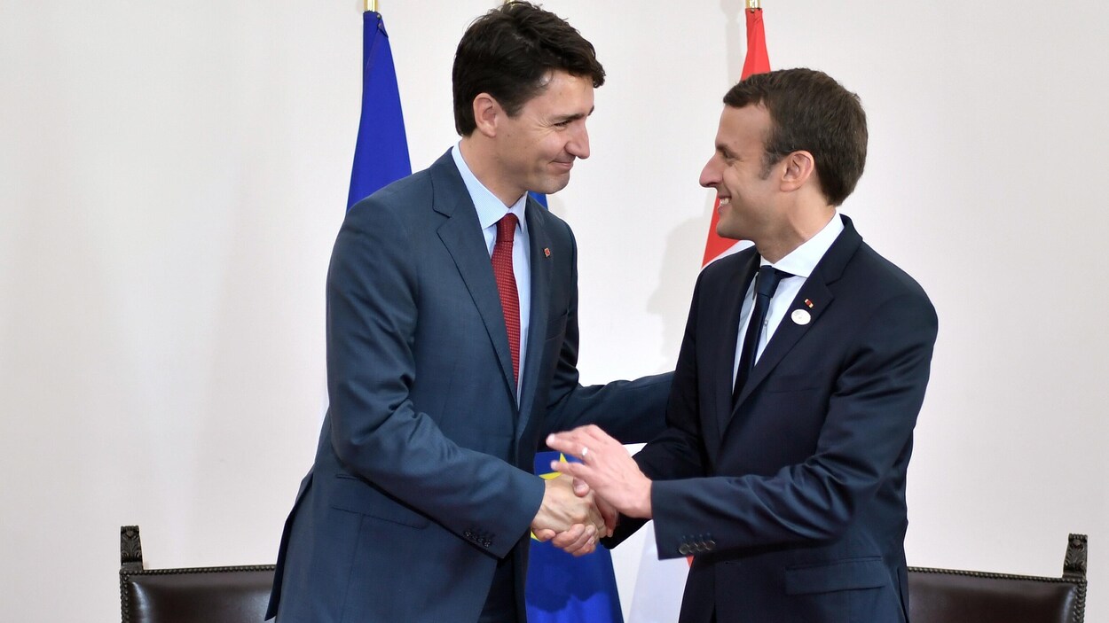 Justin Trudeau et Emmanuel Macron sont tout sourires en échangeant une poignée de main au sommet du G7 en Italie le 26 mai 2017