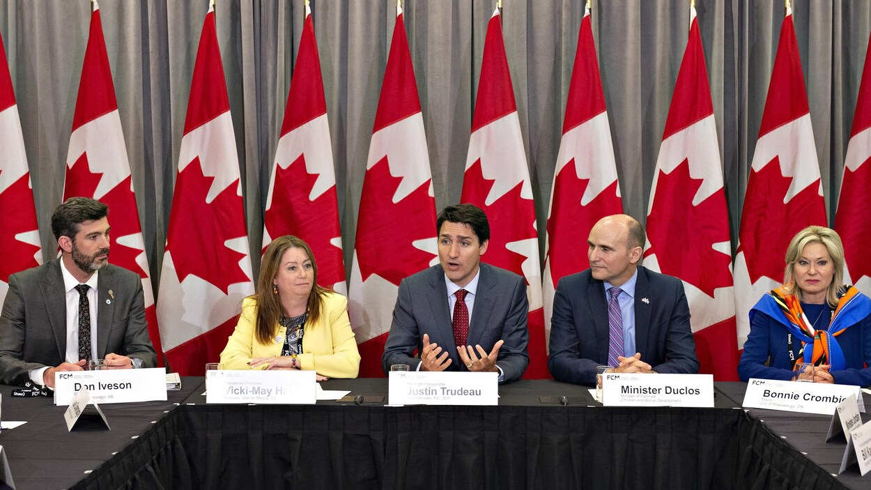 Justin Trudeau est entouré de collègues pendant une rencontre.