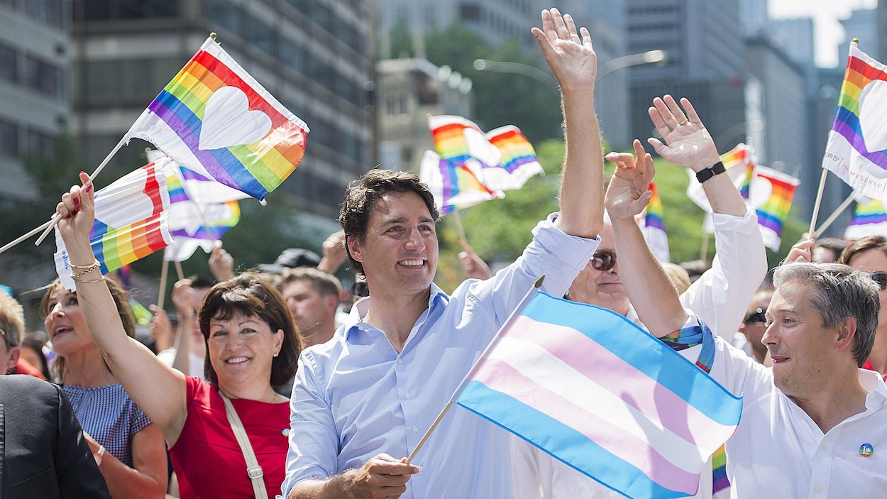 Le premier ministre canadien Justin Trudeau prend part au défilé de Fierté Montréal, un drapeau de la fierté transgenre à la main.