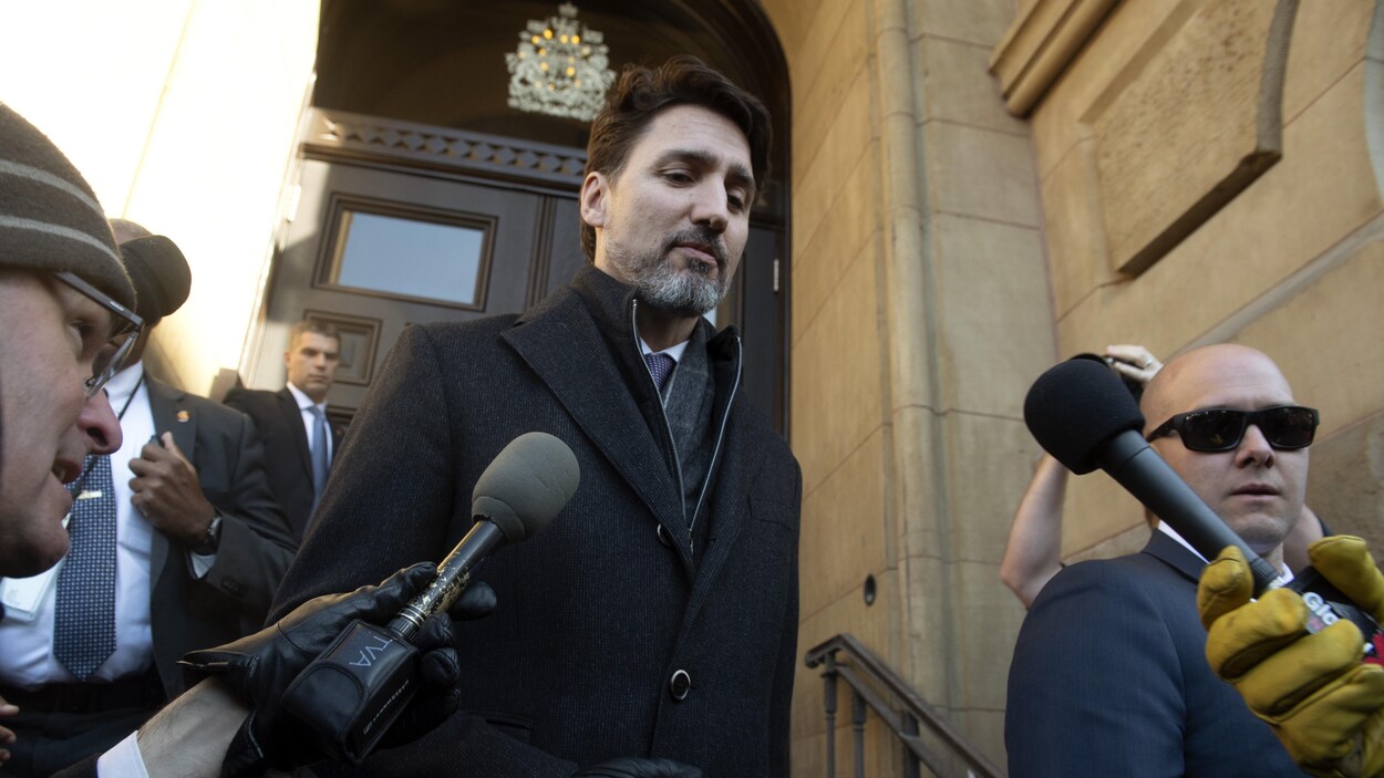 Justin Trudeau descend un escalier entouré de journalistes.
