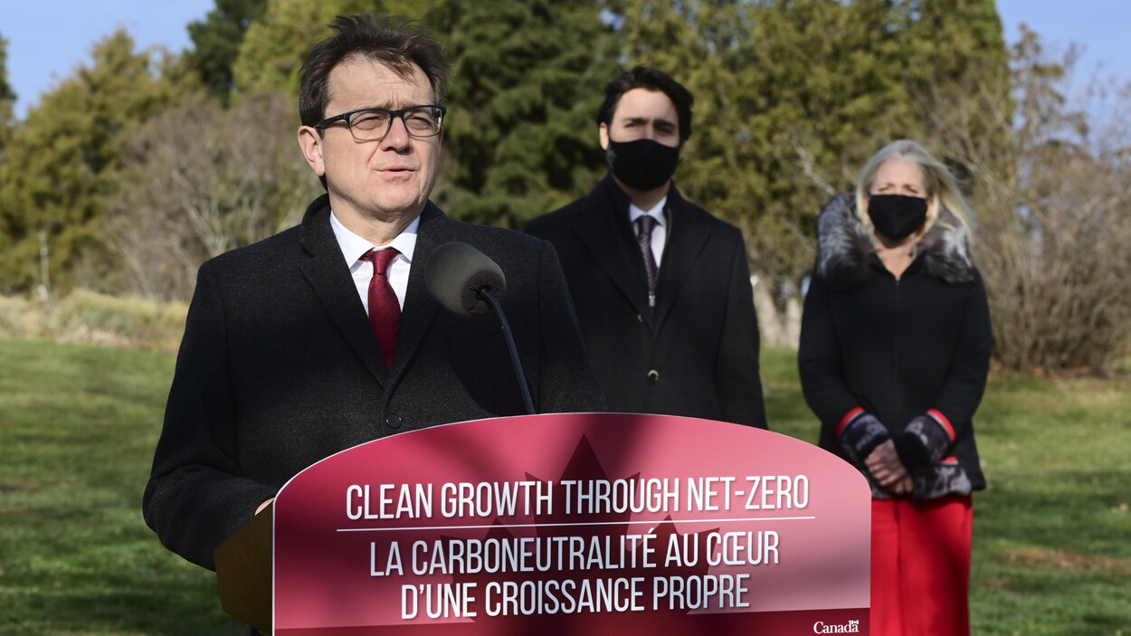 Jonathan Wilkinson parle dans un micro debout sur la pelouse devant Justin Trudeau et Catherine McKenna.