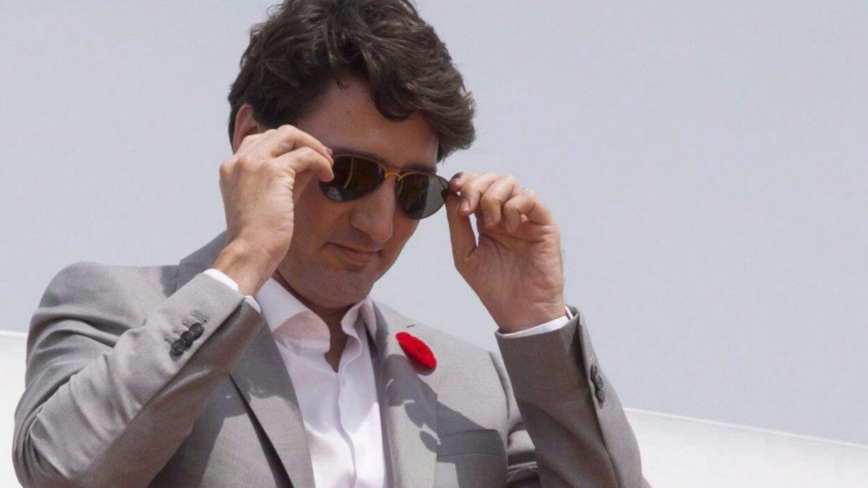 Justin Trudeau met les mains sur les branches de ses lunettes de soleil.