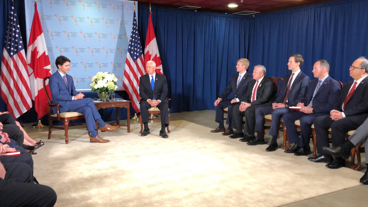 Justin Trudeau et Mike Pence sont assis dans une salle de réunion où plusieurs autres personnes se trouvent