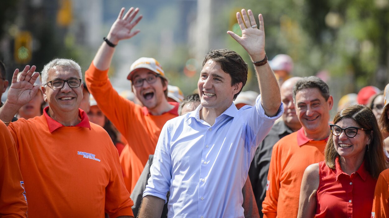Justin Trudeau salue la foule entouré de gens qui portent des t-shirts orange.