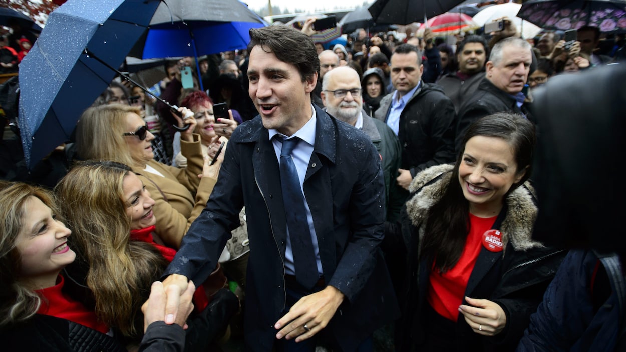 Justin Trudeau traverse la foule, sous la pluie, en serrant des mains et en souriant.