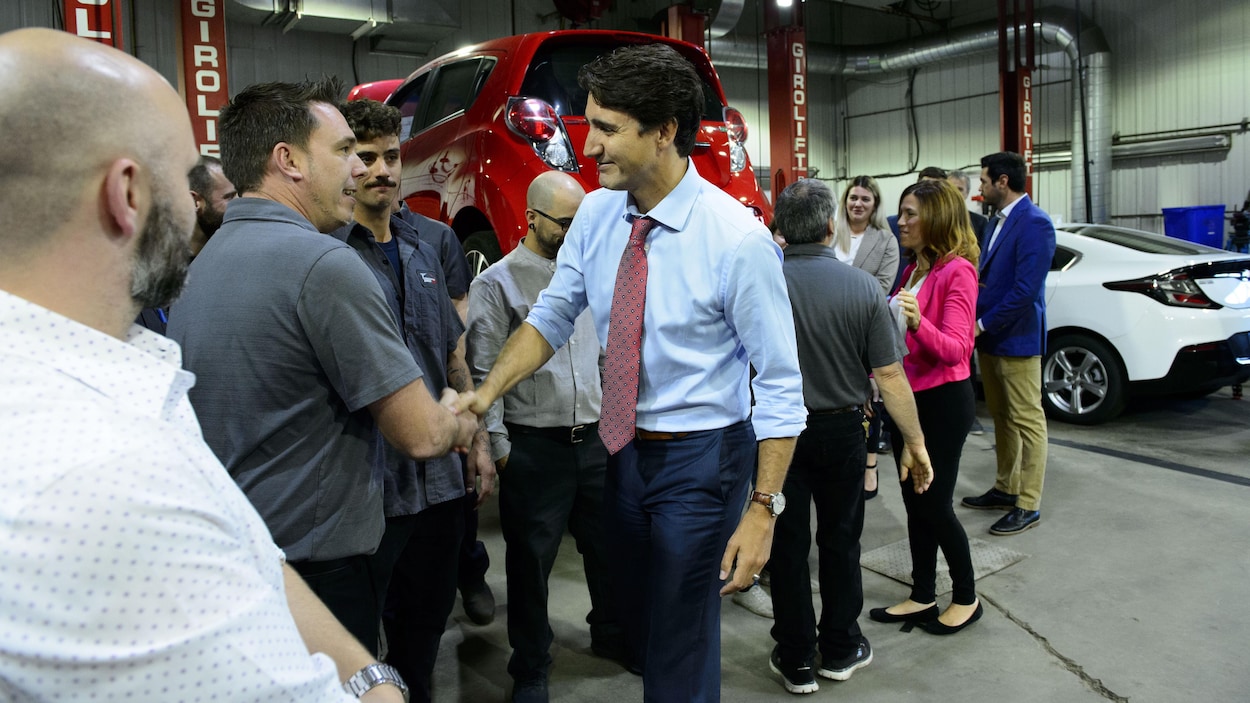 Justin Trudeau serre la main d'un homme dans un garage.