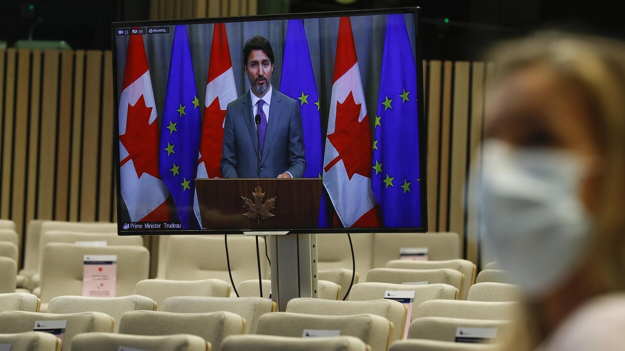 Justin Trudeau apparaît sur un écran devant une salle vide.