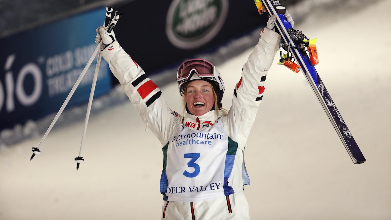 Justine Dufour-Lapointe se tient debout, ses skis dans une main et ses bâtons dans l'autre.