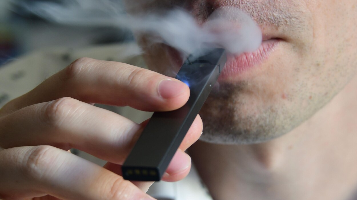 Un homme utilise une cigarette électronique.