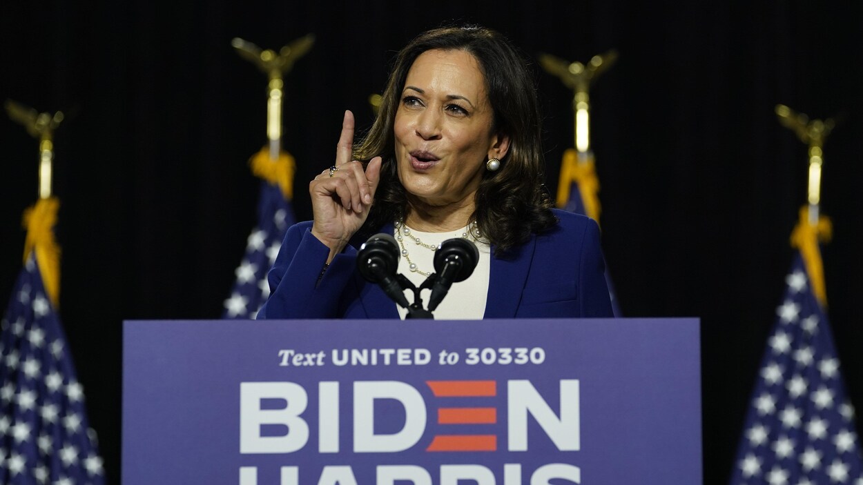 Kamala Harris parle sur une tribune l'index levé.