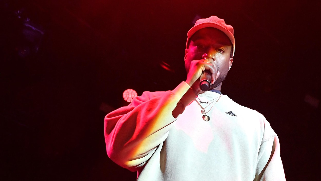 Kanye West avec un micro à la main sur scène lors d'un événement promotionnel.