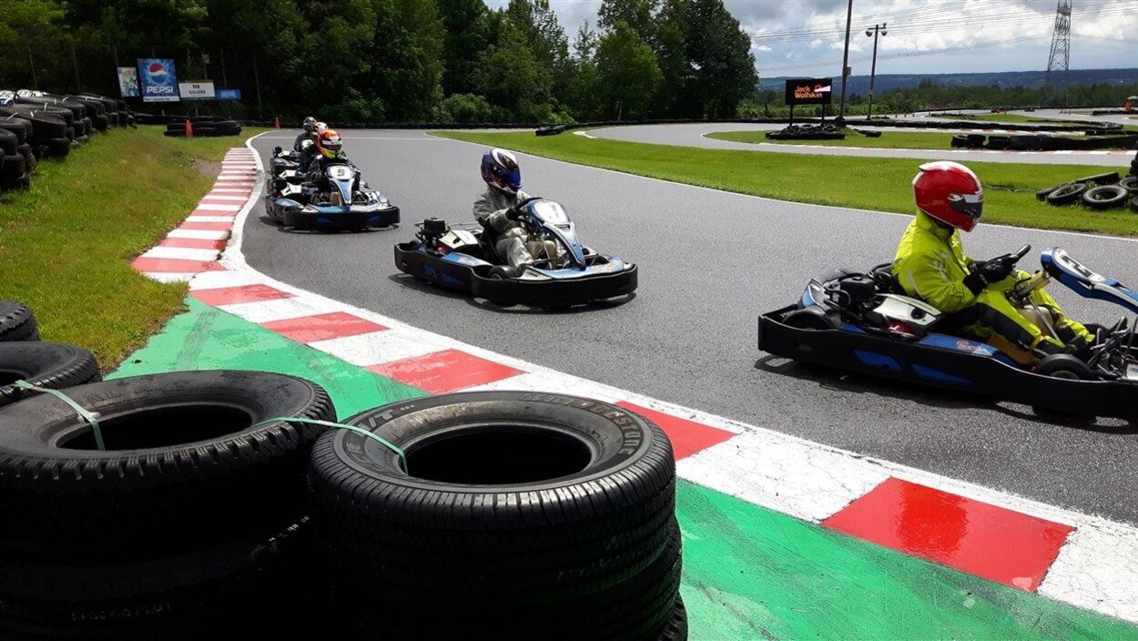 Une piste de karting entourée de pneus sur laquelle on peut voir des pilotes pendant une course