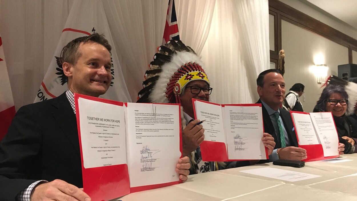 Trois hommes montrent leur entente signée.