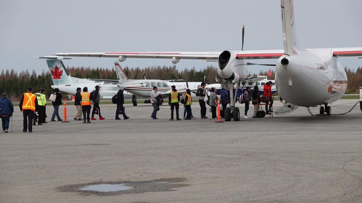 Des gens sur le tarmac qui montent à bord d’un avion.