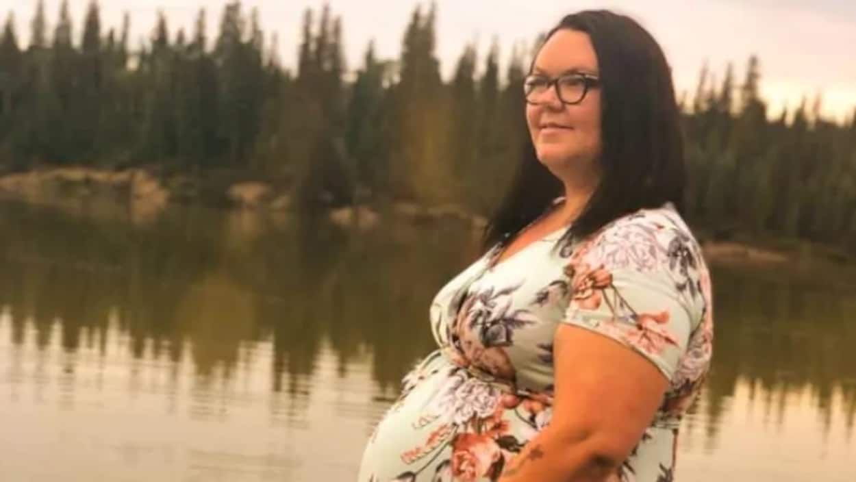 Une femme enceinte est de profil devant un lac.
