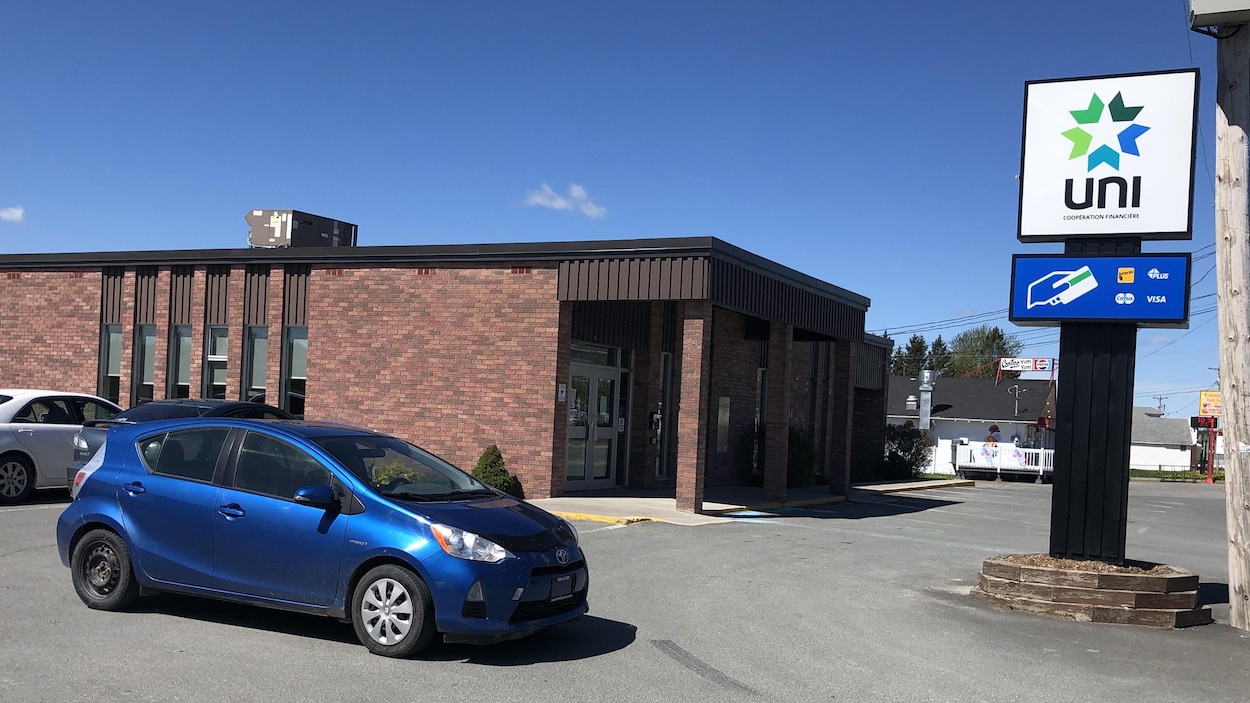 Trois voitures garées devant un petit édifice recouvert de briques.