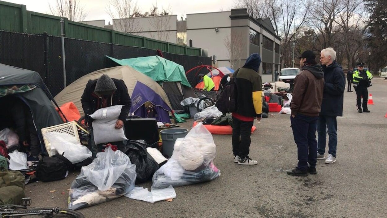 Des agents de la Ville de Kelowna surveillent un sans-abri alors qu'il plie bagage.