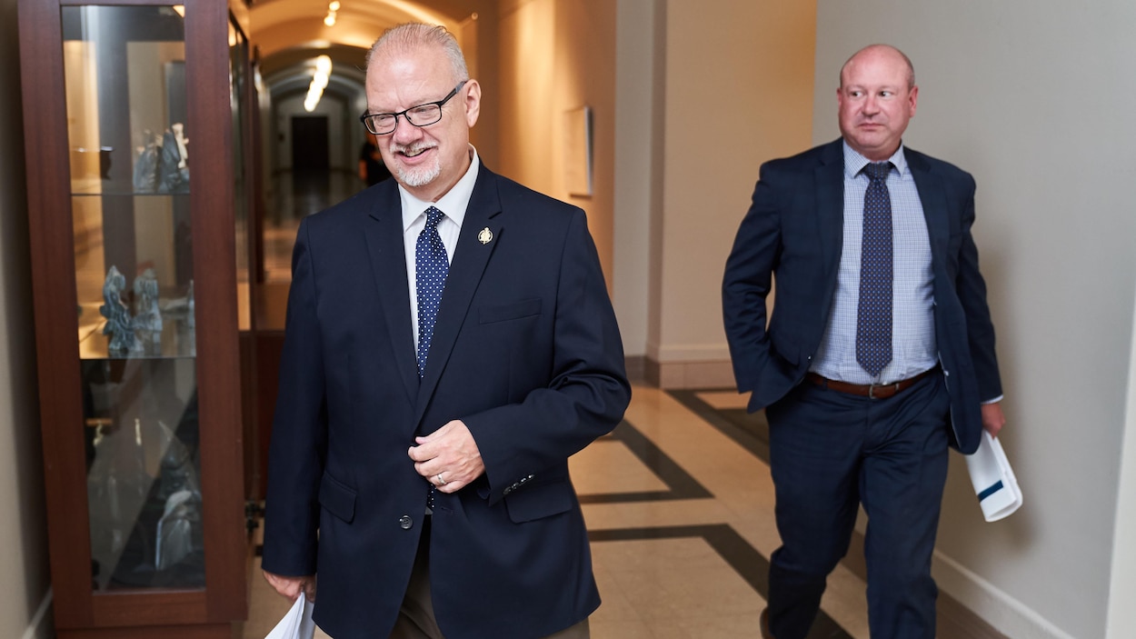 Deux hommes marchent dans un corridor.