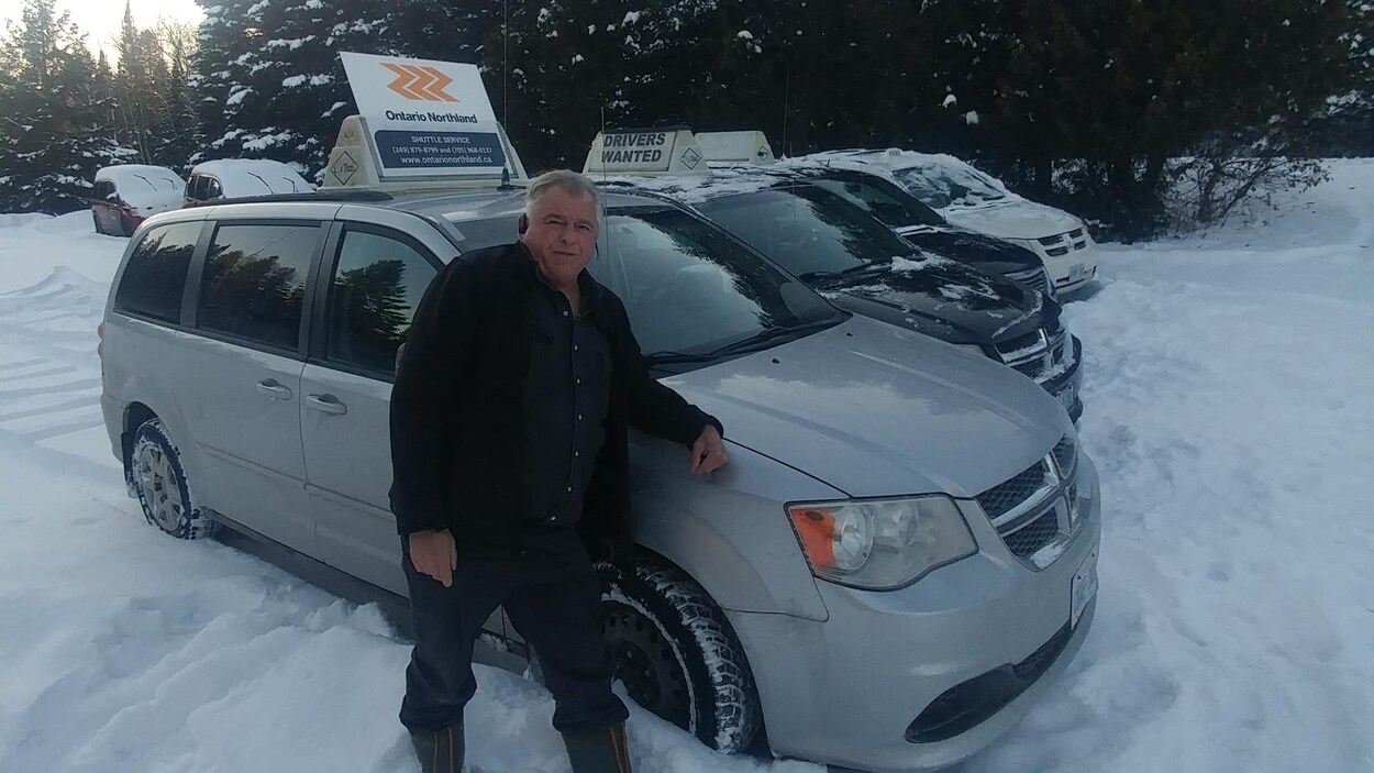 Un homme photographié devant une flotte de fourgonnettes en hiver.
