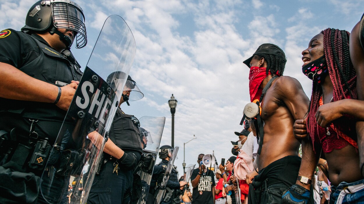 Des manifestants font face à des policiers en tenue antiémeute.