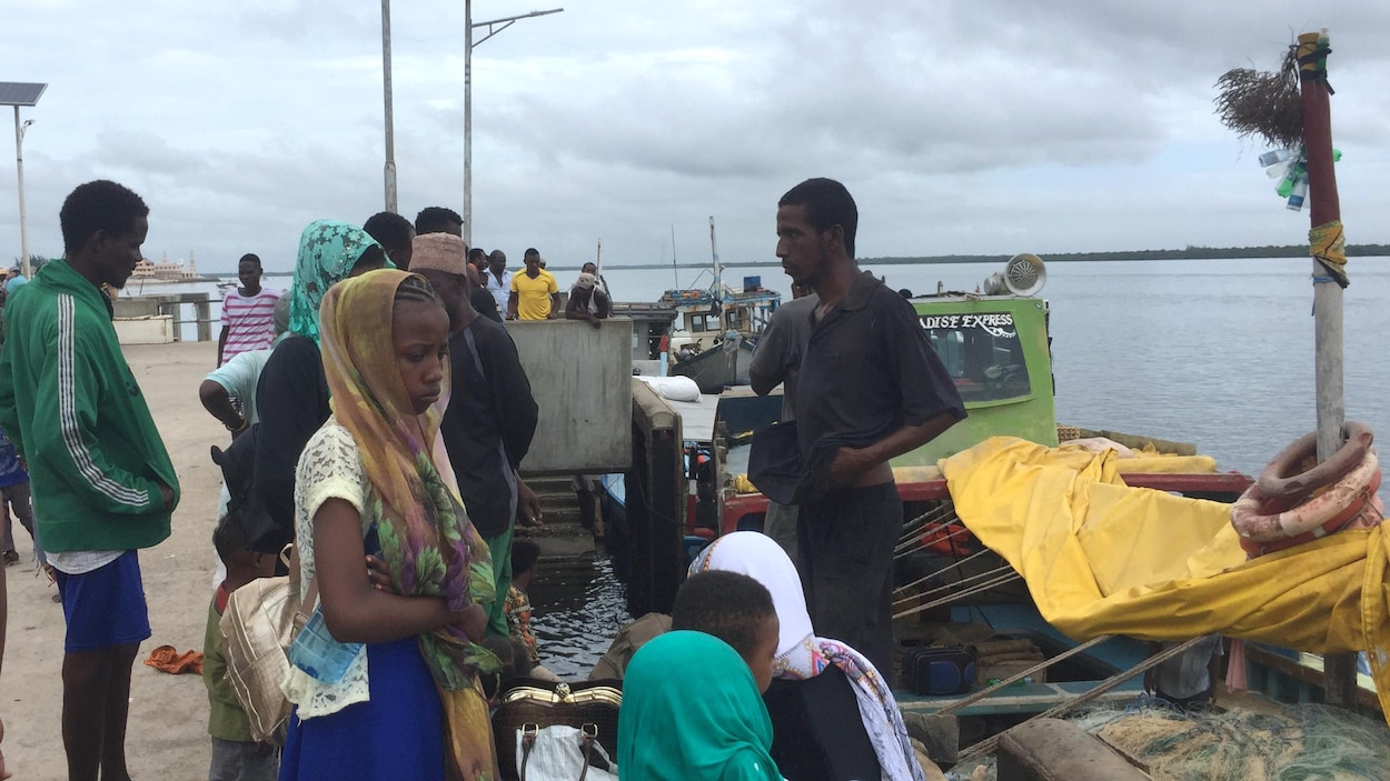 Hommes, femmes et enfants attendent sur un quai.
