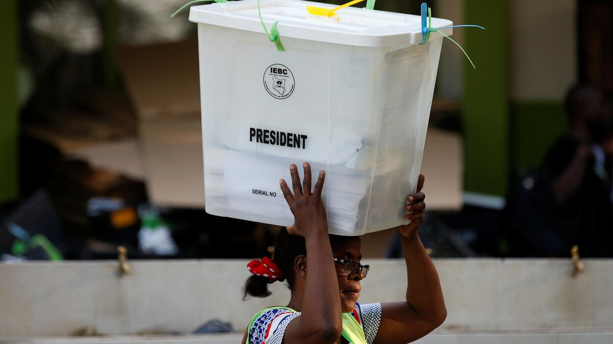 Une agente de la Commission de délimitation des circonscriptions électorales transporte une boîte de scrutin vers un centre de dépouillement des votes à Mombasa au Kenya. Une agente de la Commission de délimitation des circonscriptions électorales transporte une boîte de scrutin vers un centre de dépouillement des votes à Mombasa au Kenya.